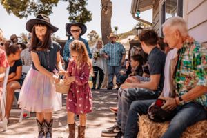 Crowd enjoying outdoor celebration with rustic decor and natural lighting.