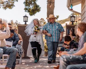 Guests mingling at rustic outdoor celebration with decorative lighting.