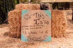Decorative signs with romantic messages displayed on hay bales in a garden setting.