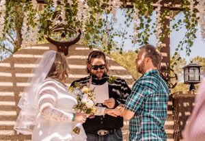 Outdoor wedding venue decorated with turquoise drapes and natural lighting.