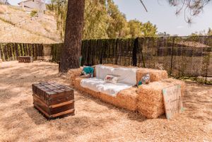 Natural outdoor setting with hay bales and wooden decorations arranged for an event.