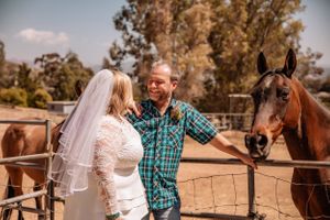 A rustic outdoor wedding scene with horses and natural landscape.