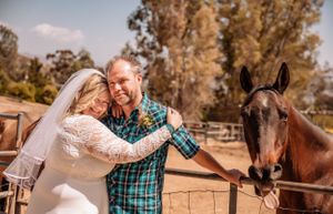 A romantic countryside photo session with horses and wooden fencing.