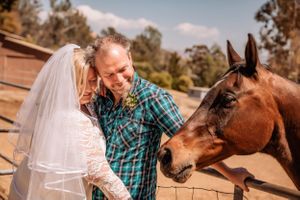 A couple shares a romantic moment with their horse during a rustic outdoor photoshoot.