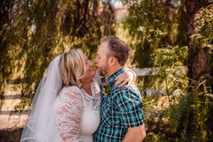 A couple in casual western attire sharing an intimate moment outdoors in a rustic setting.