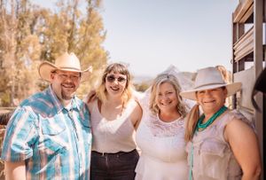 Happy group poses together outside in western-style clothing on a sunny day.