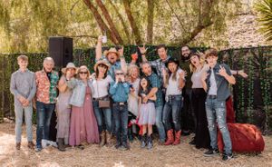 Family gathering outdoors with people dressed in coordinating outfits of pink, blue and denim tones.