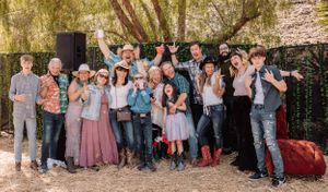 Extended family portrait with multiple generations wearing coordinated casual attire in an outdoor setting.
