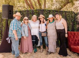 Large family group photo with everyone wearing coordinated pink, blue and denim outfits outdoors.
