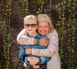 Sweet embrace between two people wearing white lace and denim against vine-covered wall.