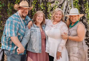 People in western casual wear and sun hats gather for a cheerful outdoor photo shoot.