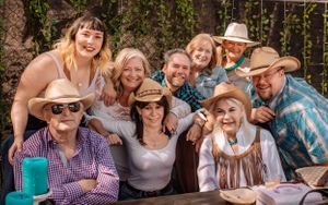 Group photo session outdoors with people wearing western-style clothing and hats.