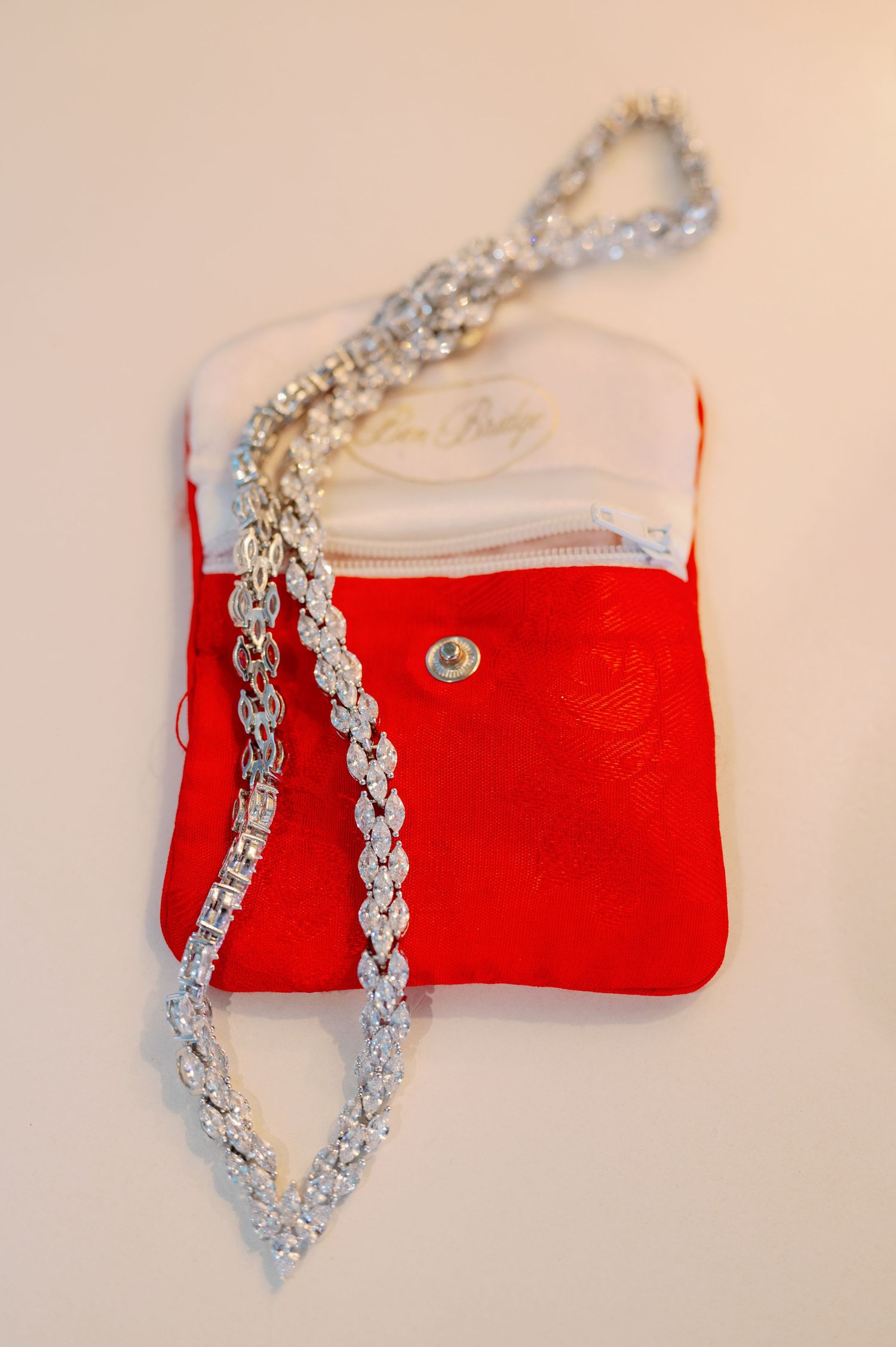 Crystal necklace displayed on a red velvet pouch against white background.