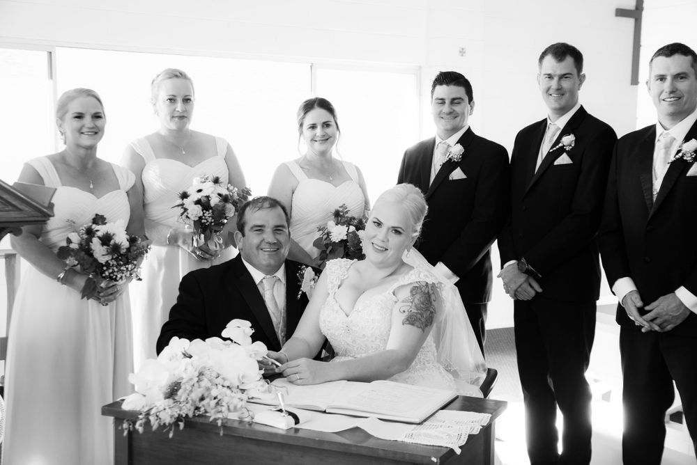 A formal wedding ceremony taking place with attendees dressed in black and white attire.