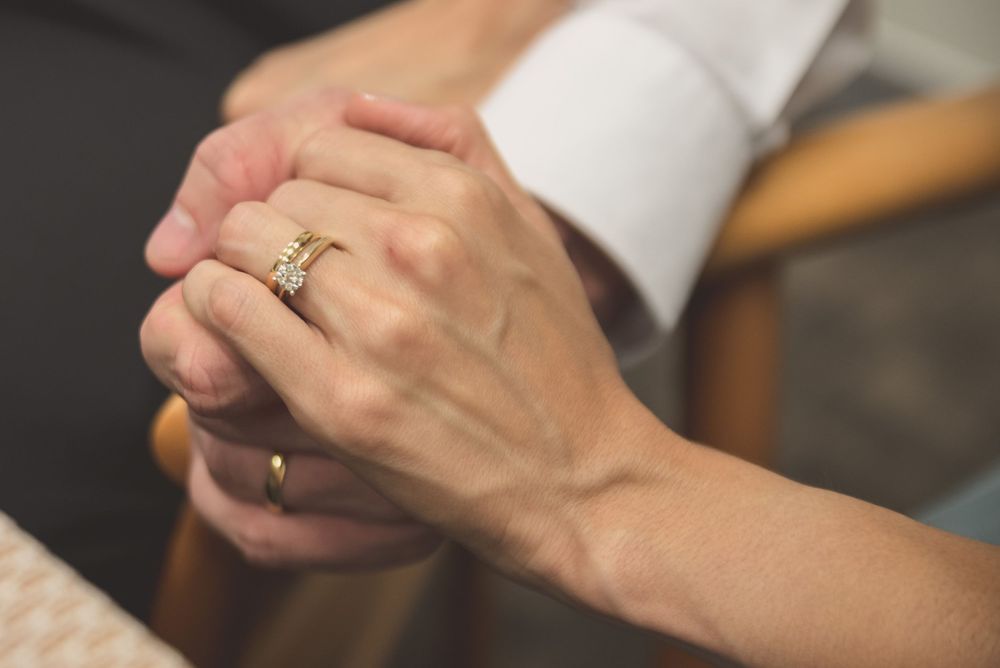 Close-up shots of hands displaying wedding rings against a neutral background.
