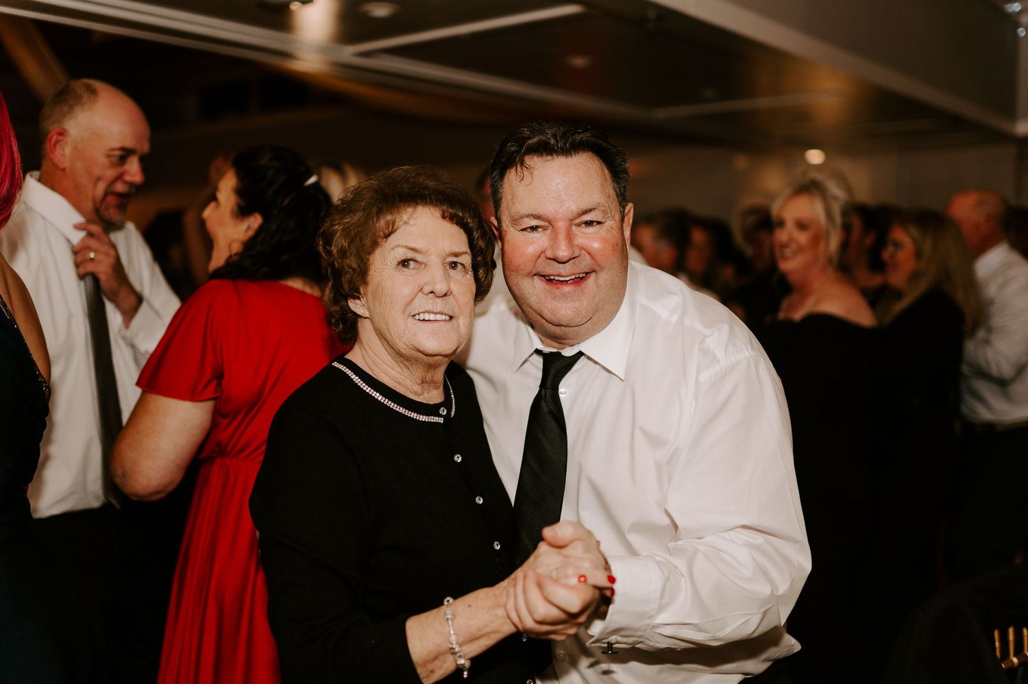 Candid moment of dancing couples enjoying themselves at an evening reception celebration.
