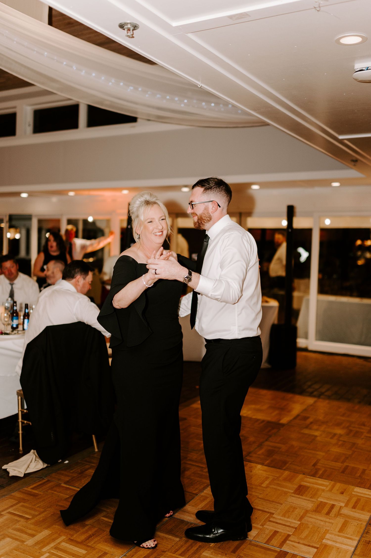 Elegant dance partners sharing a moment on the wooden dance floor at a formal event.