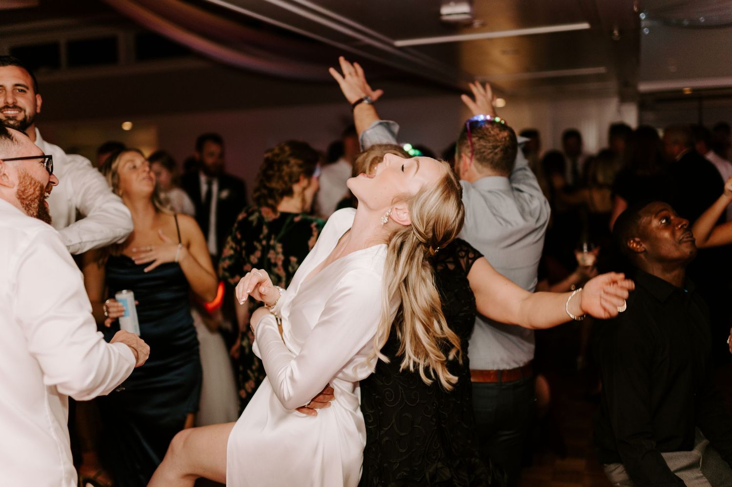 Lively dance floor scene at a wedding reception with guests celebrating.