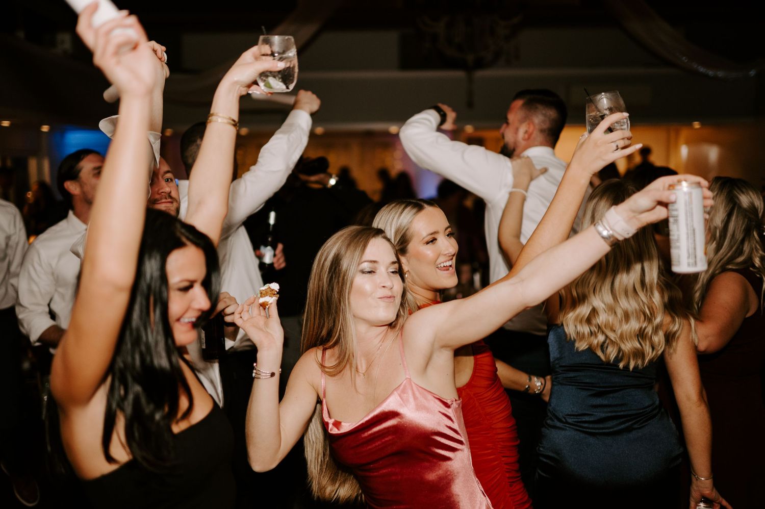 Energetic crowd dancing and having fun at an indoor wedding reception.