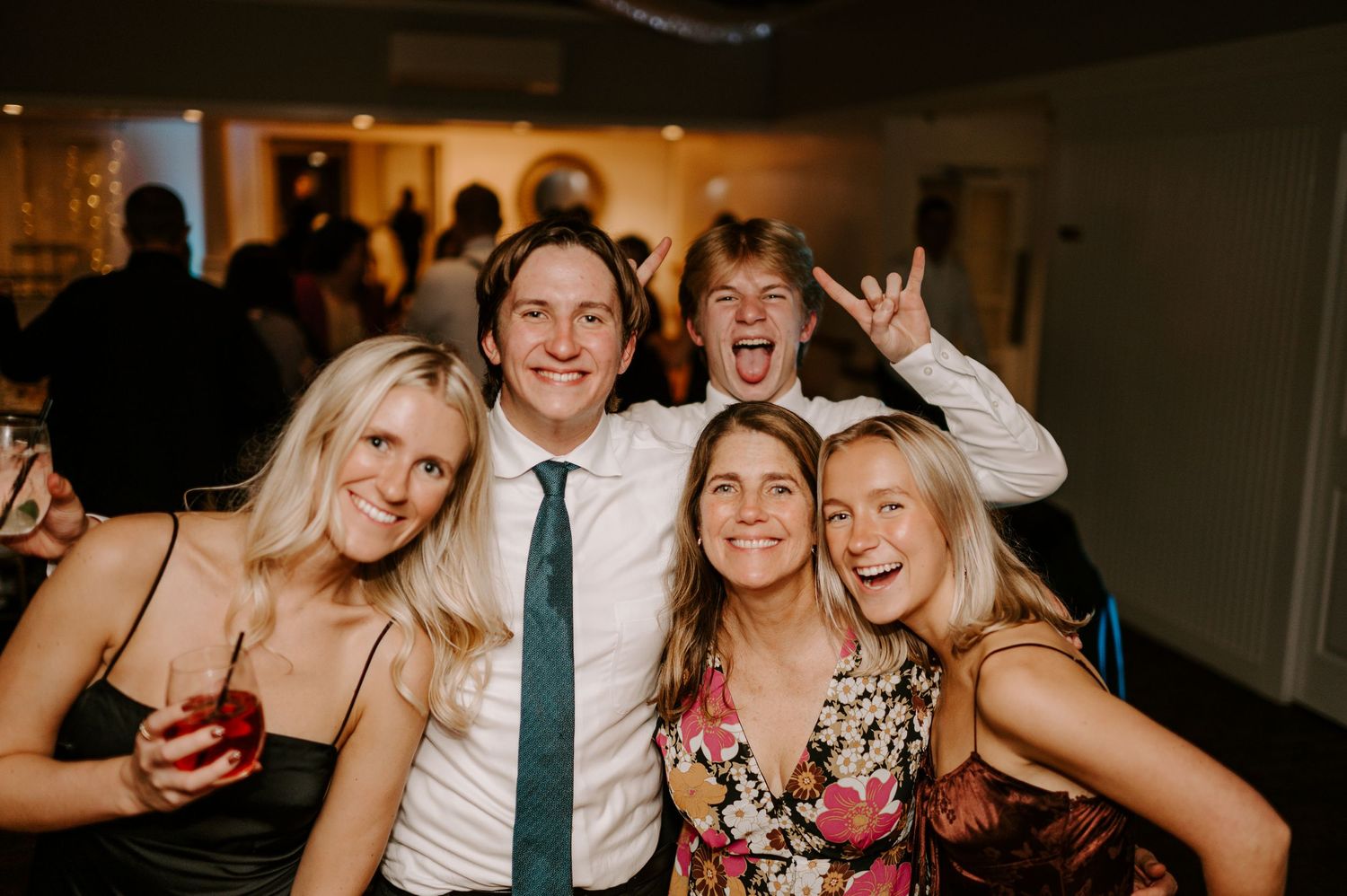 Wedding reception guests dancing and celebrating on a dimly lit dance floor.