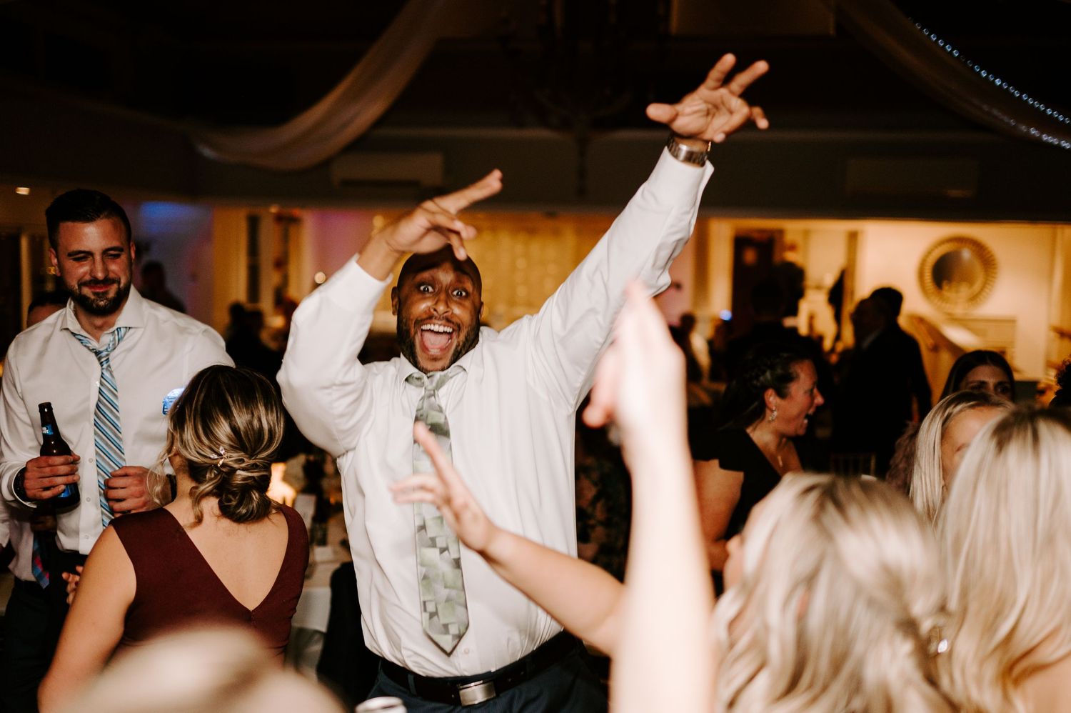 Wedding party guests dancing together in a dark reception venue.