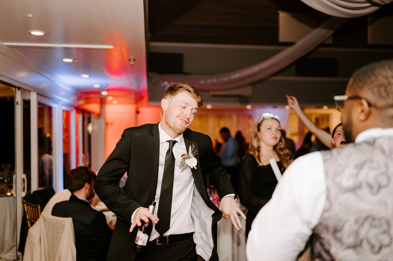 Wedding guests dancing under ambient lighting at an indoor reception venue.