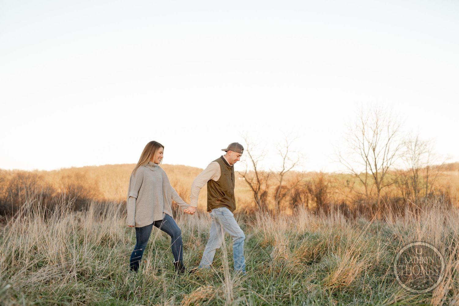 A couple takes a casual stroll together through tall grass in a scenic autumn field.