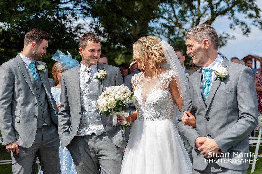Bride and groom smiling at each other in the outdoor ceremony at west tower Ormskirk wedding venue.