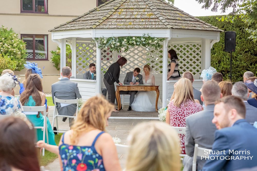 Bride and groom sign the register in the pergola at west tower country house hotel.