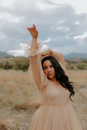A flowy peach dress twirls in a desert setting with mountains in the distance.