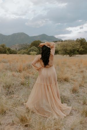 A peachy dress moves elegantly through desert terrain with mountains in the background.