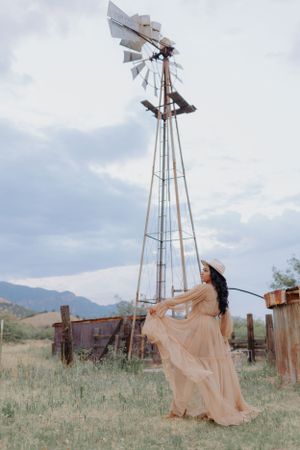 A flowing peach dress creates dramatic movement against a windmill and desert landscape.
