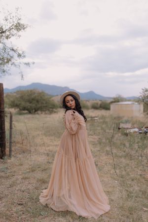A romantic peach-colored maxi dress twirls in a desert landscape with mountains in the background.