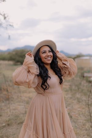 A romantic desert photoshoot featuring a flowing peach dress and beige hat.