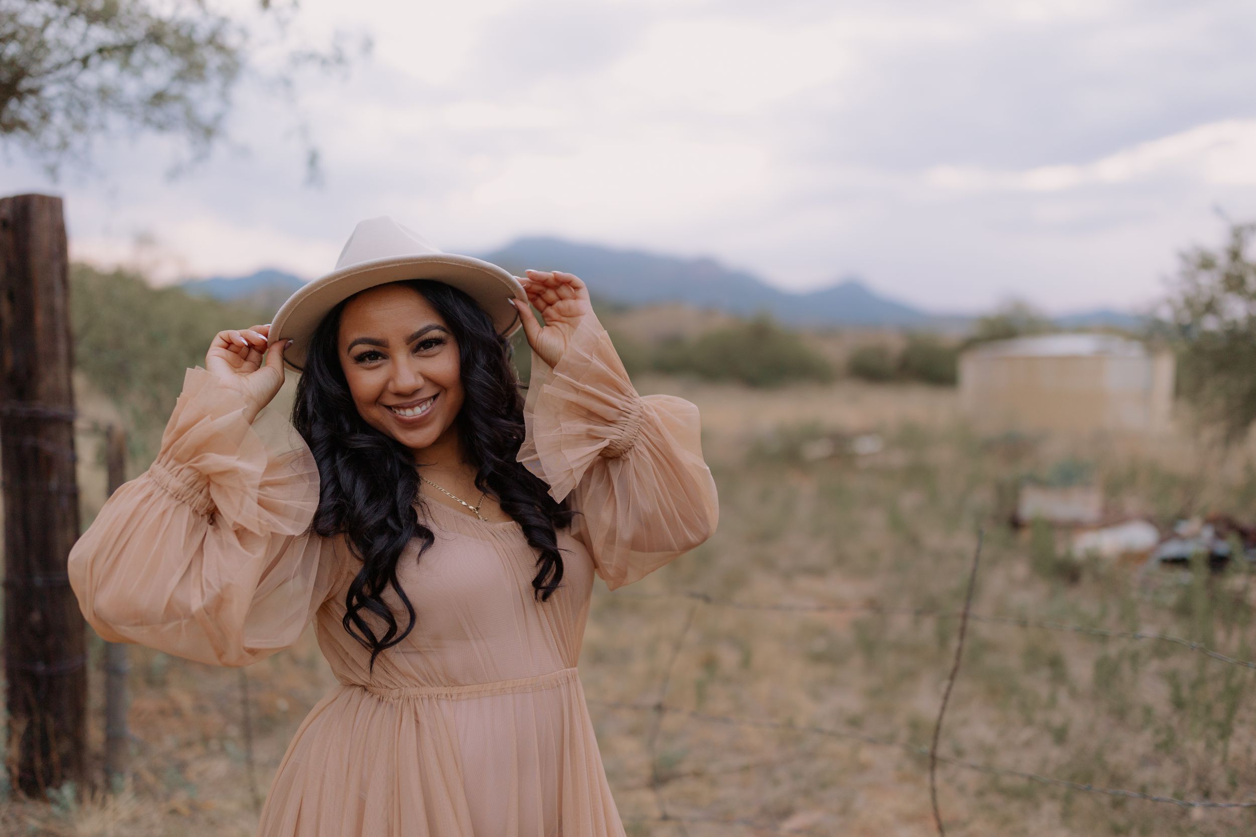 A flowing pink dress twirls against a desert mountain backdrop on a sunny afternoon.