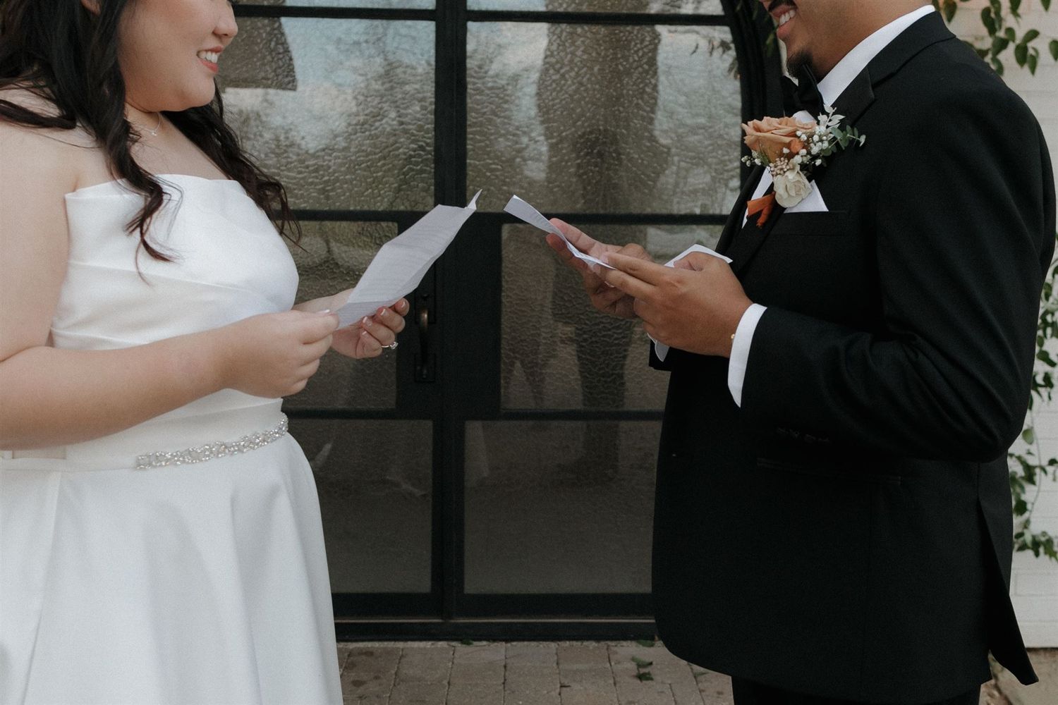 Close-up of couple exchanging vows while reading from papers during wedding ceremony.