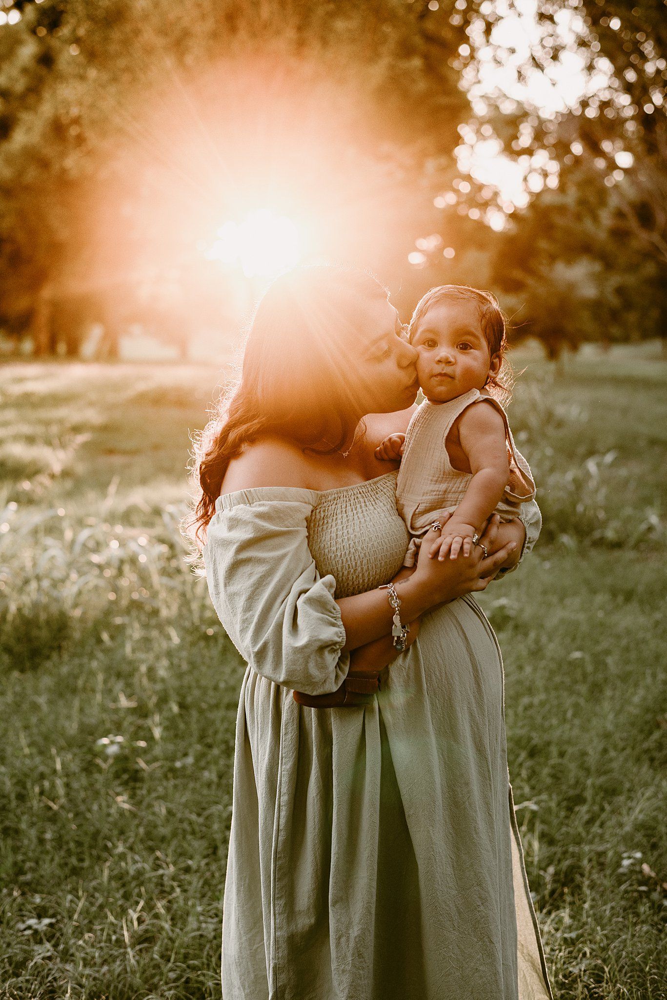 Golden sunlight illuminates a tender moment between parent and child in an outdoor setting.