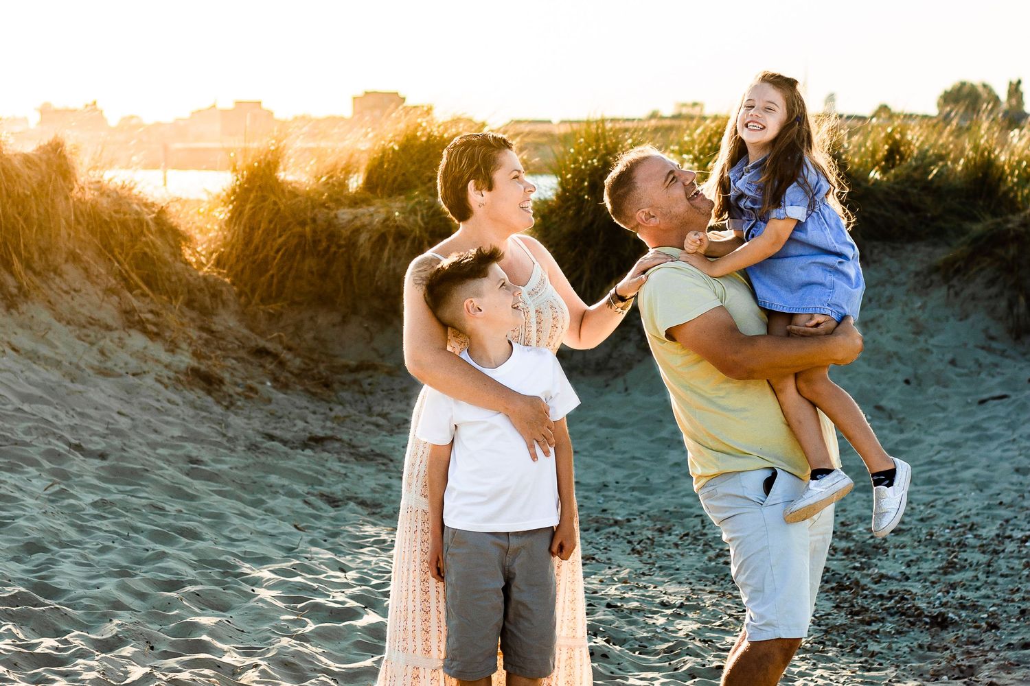 On a beach on Hayling Island a family stands in the warm sunset laughing.