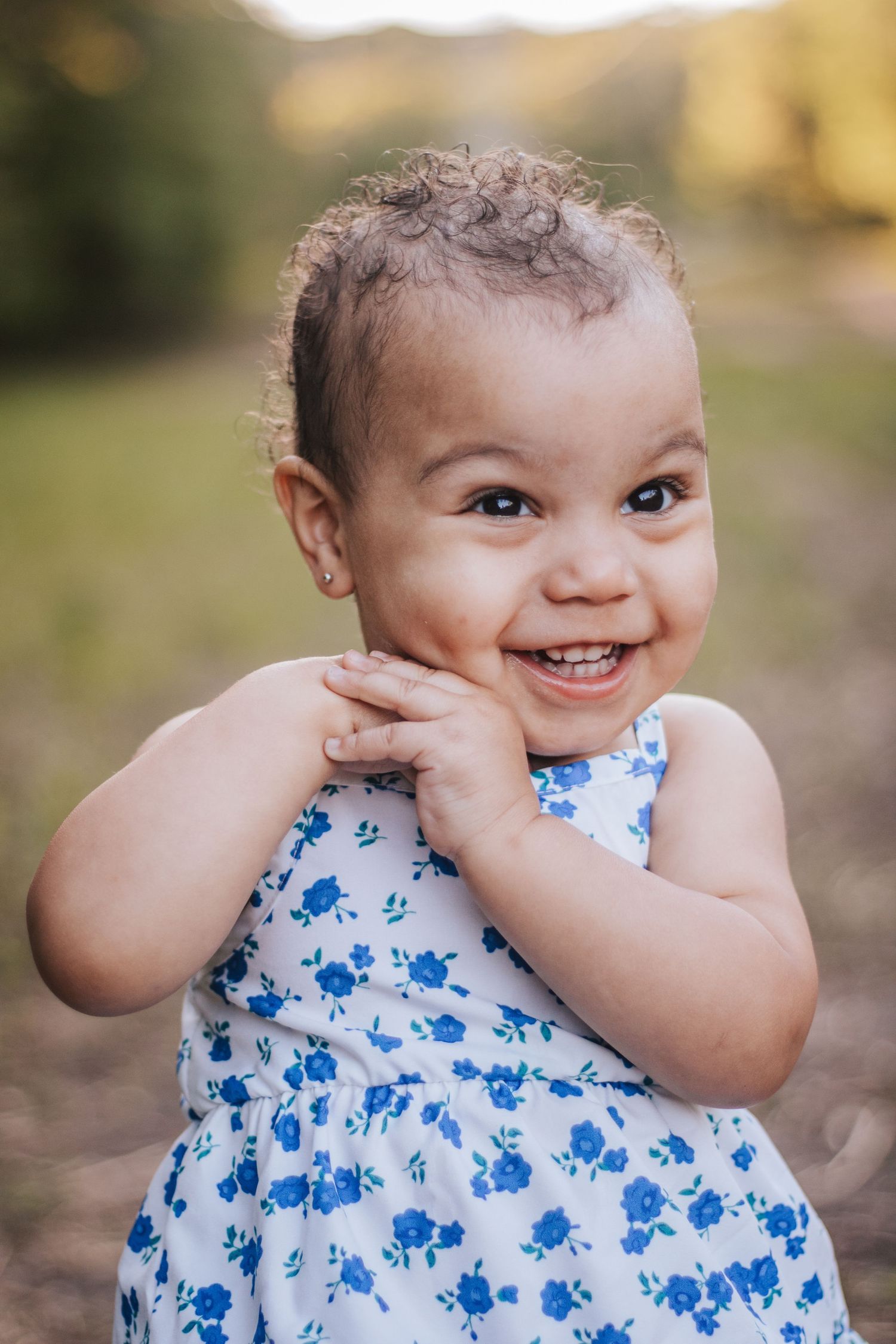 Baby in blue floral dress making silly faces at camera.
