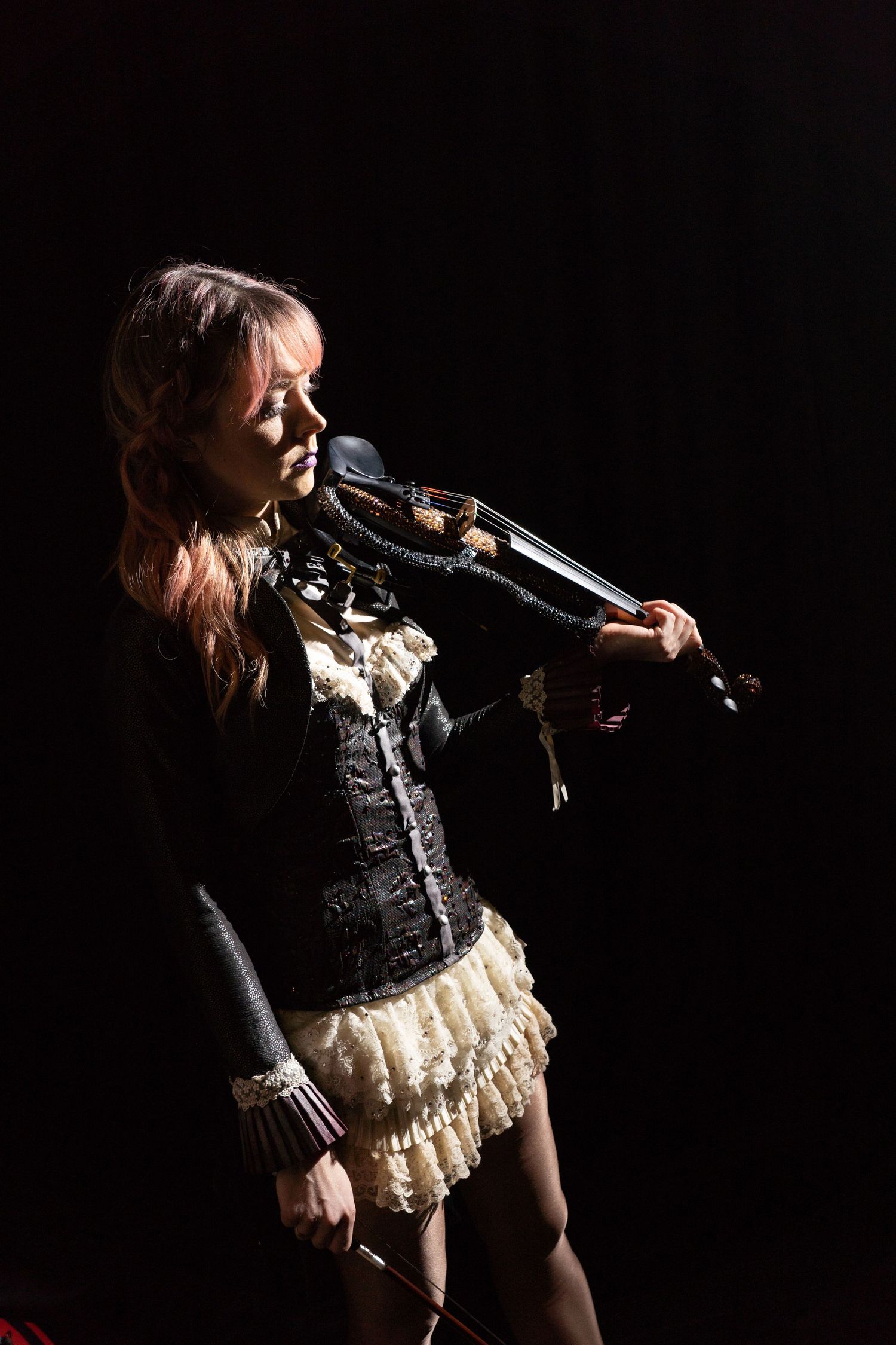Dramatic stage performance with performer in lace outfit illuminated by spotlight.