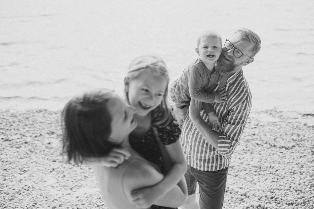 Playful black and white family portrait captured on a beach.