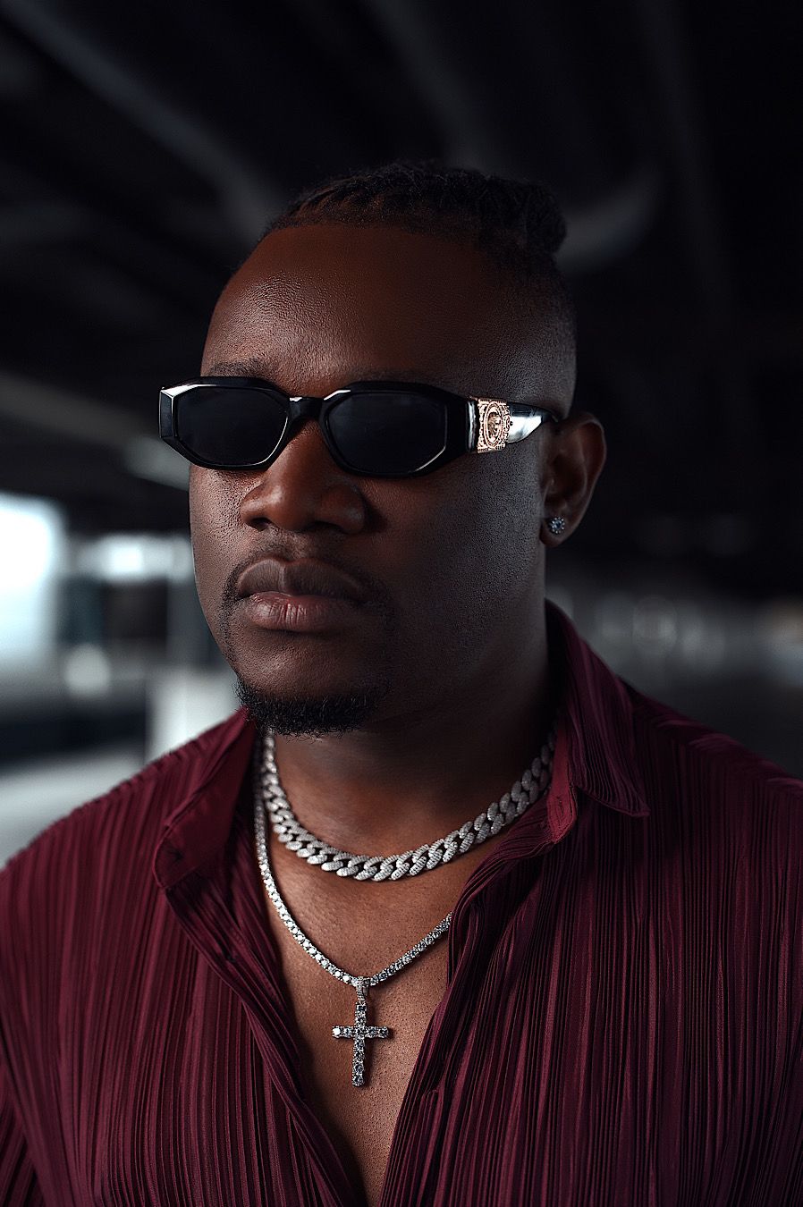 Stylish portrait of person wearing sunglasses, burgundy shirt and silver chain necklace.