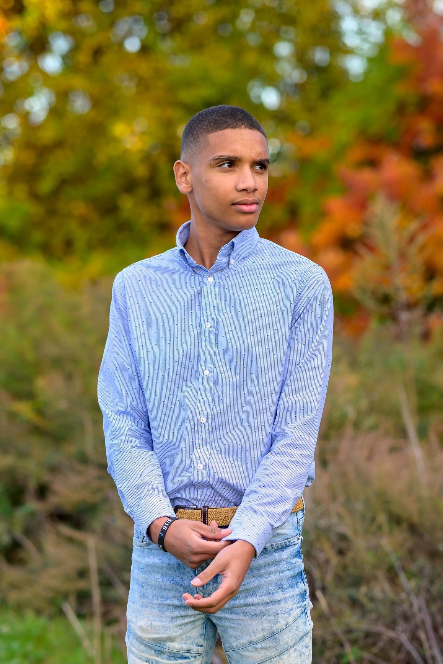 A young Dominican man posing for his high school senior portrait in autumn.