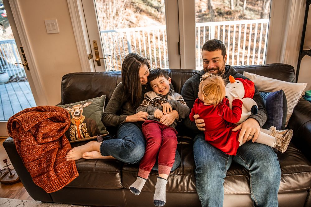Family lounging together on couch during holiday season with Christmas tree.