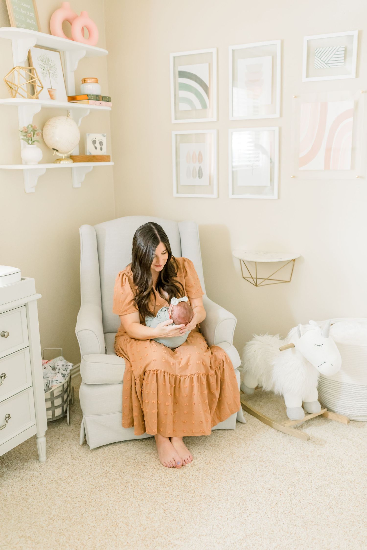 Cozy nursery corner with white glider, floating shelves, and modern pastel wall art.