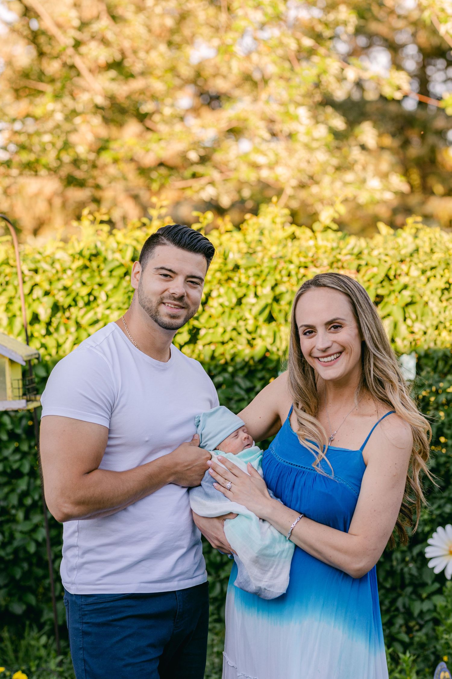 A newborn photography session captured by Katie Crane, featuring a man and woman holding their baby in Brampton, Ont..