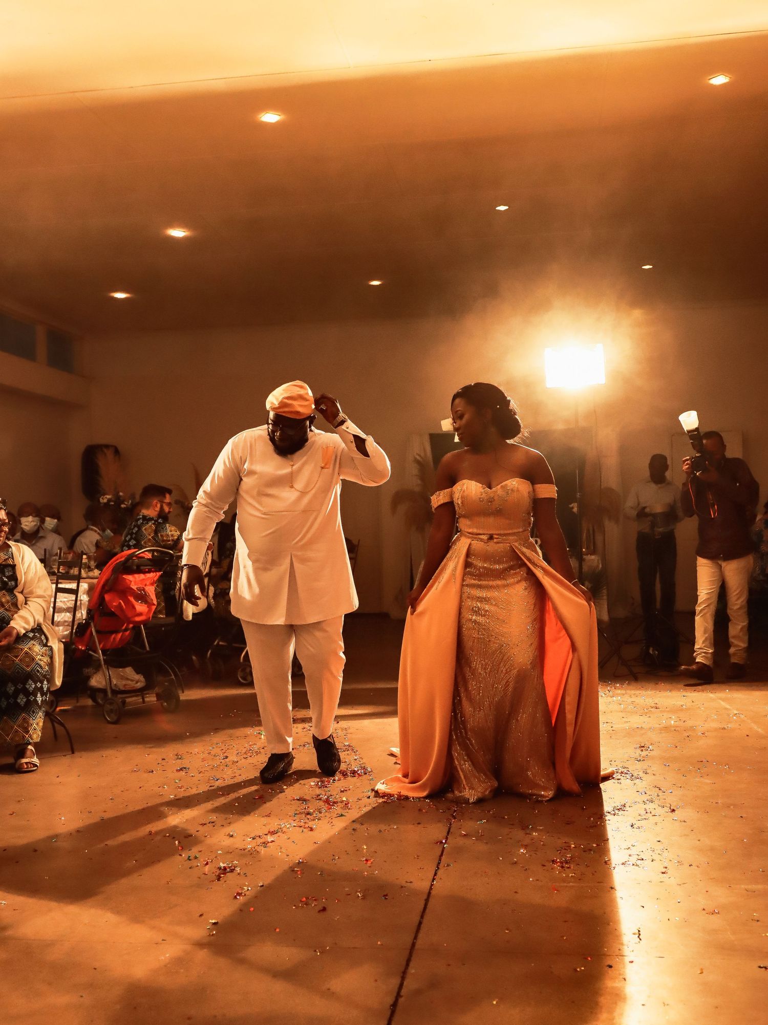 Candid dance moment at formal event with duo in white and orange attire.
