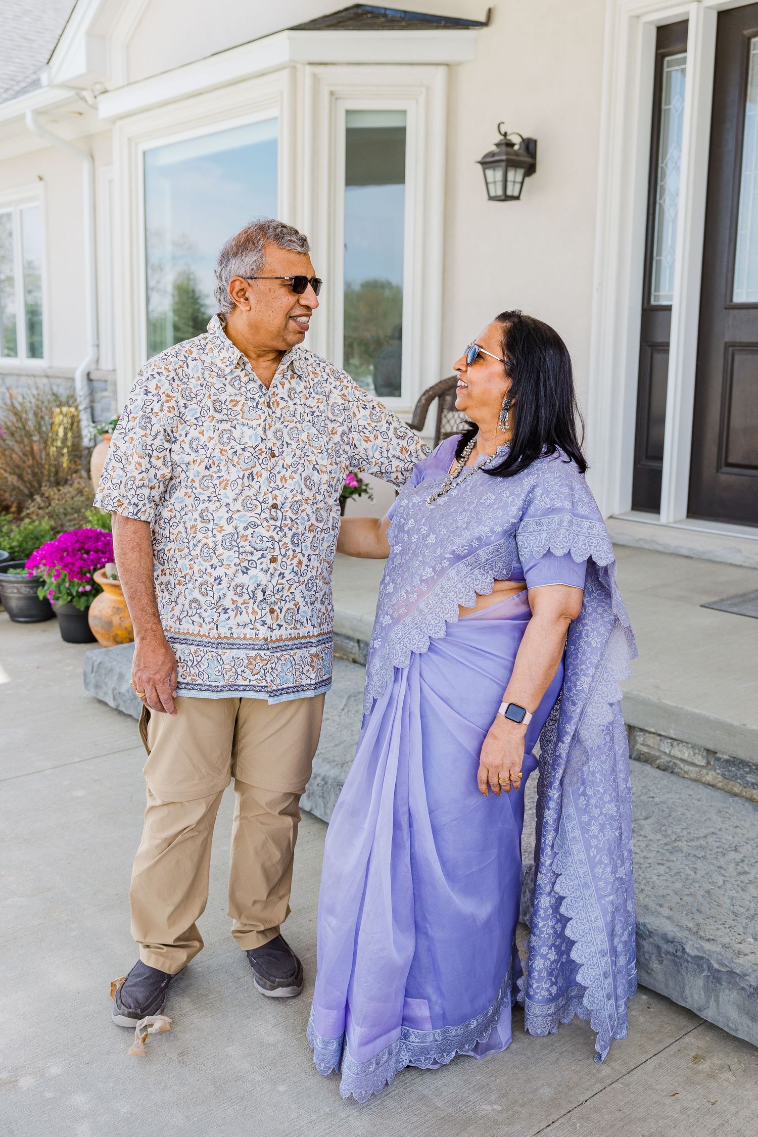 Couple in coordinated outfits sharing a laugh together on their front porch steps.
