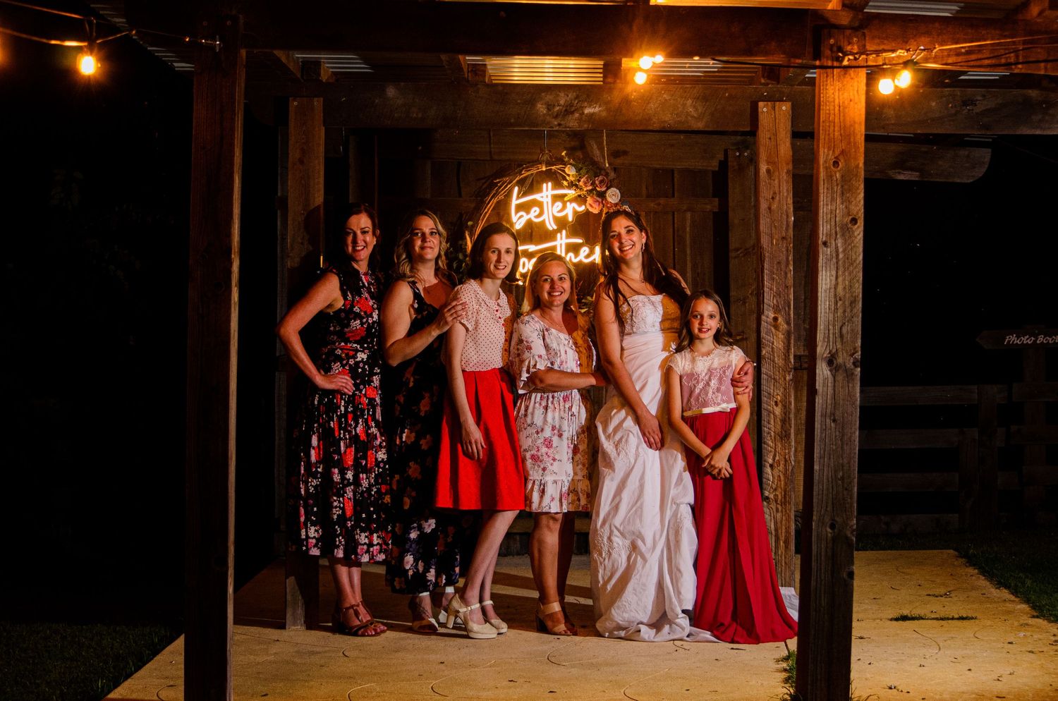 A celebratory group poses together in formal attire inside a dimly lit rustic venue.