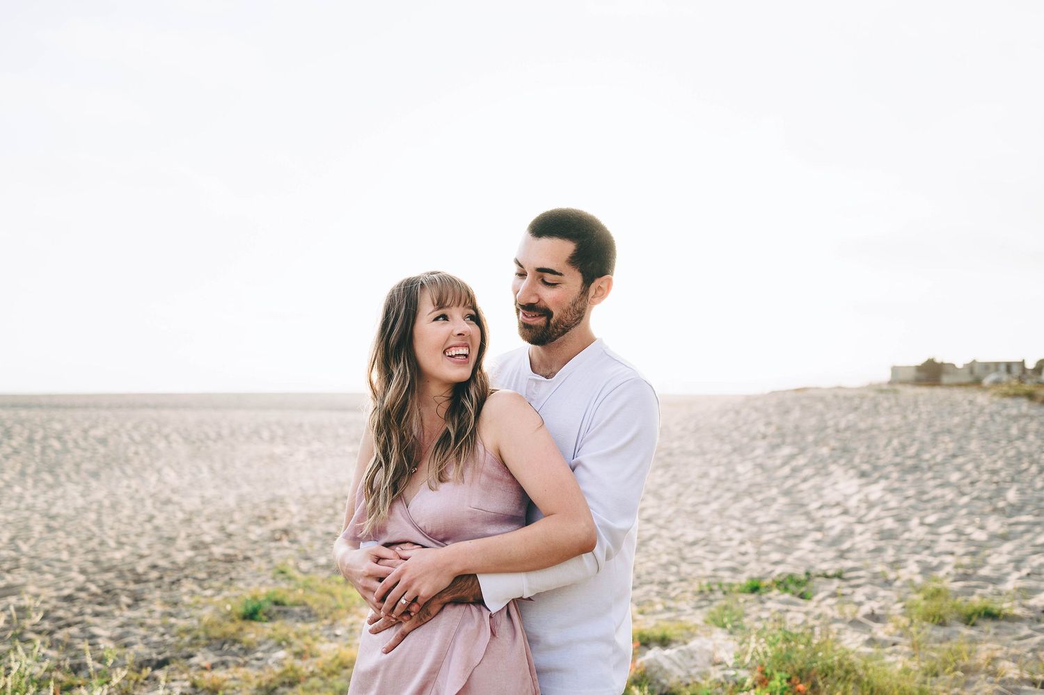 Romantic couple laughing together in bright natural setting.